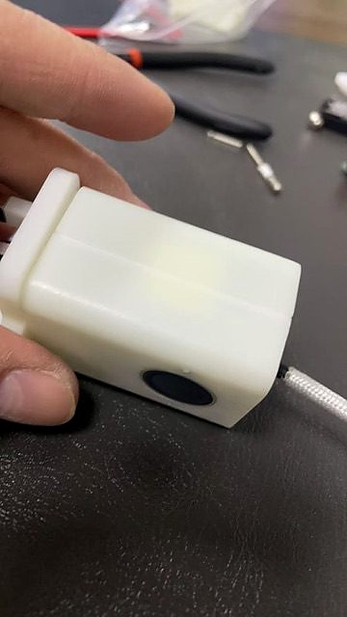 Smooth white 3D-printed Charlie Charger prototype held in hand, showing fingerprint sensor window